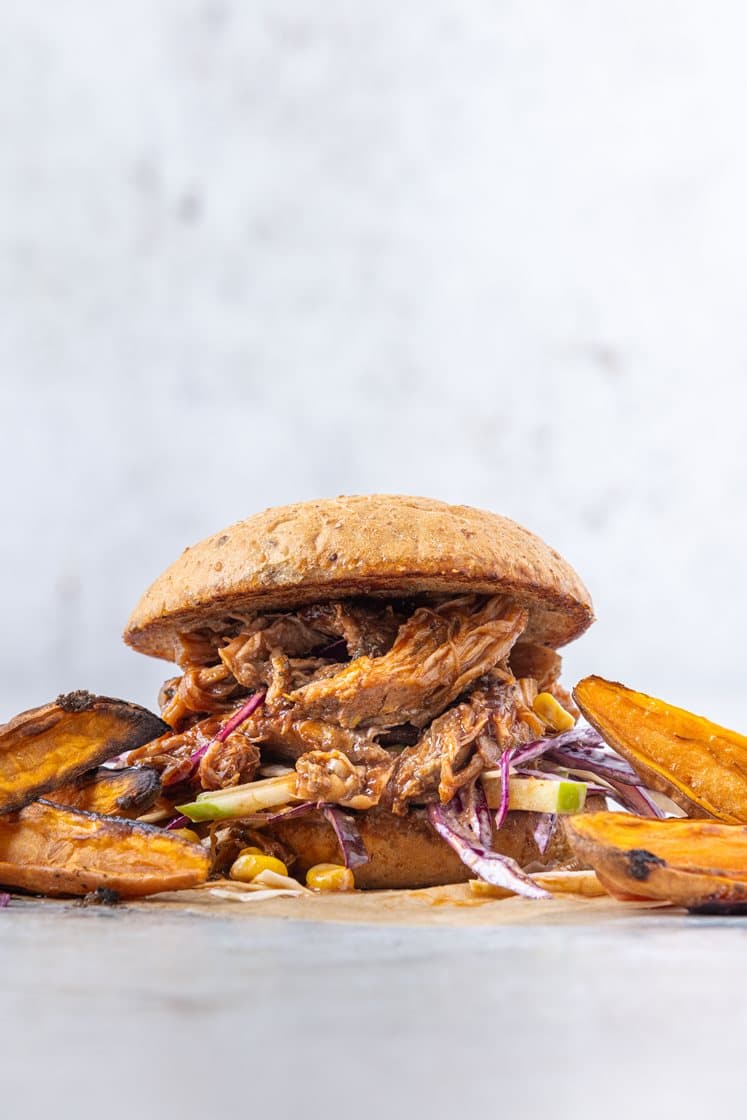 Pulled pork-burger med barbecuesaus, servert med maiscoleslaw og ovnsbakte søtpotetbåter