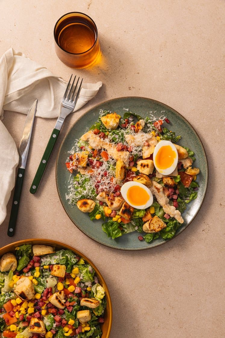 Cæsarsalat med kyllingfilet, sprøstekt bacon, kokte egg og brødkrutonger, toppet med Grana Padano