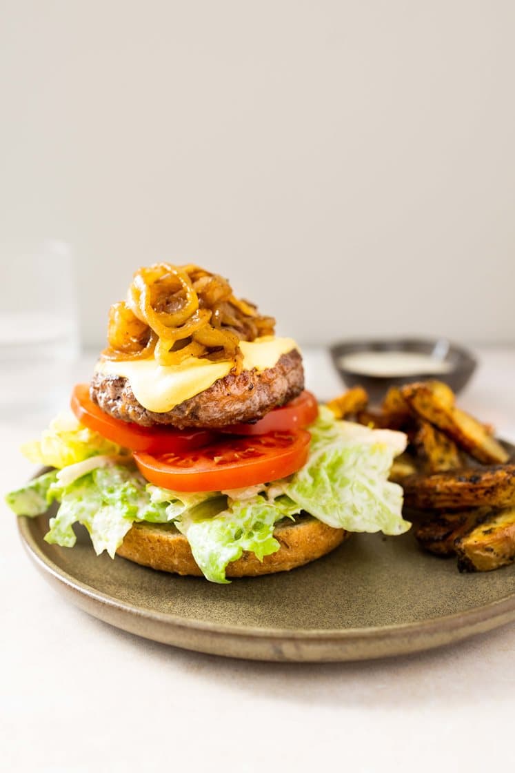 Homestyleburger med karamellisert løk og dijonsennep, tomatsalat i cæsardressing og urtefries