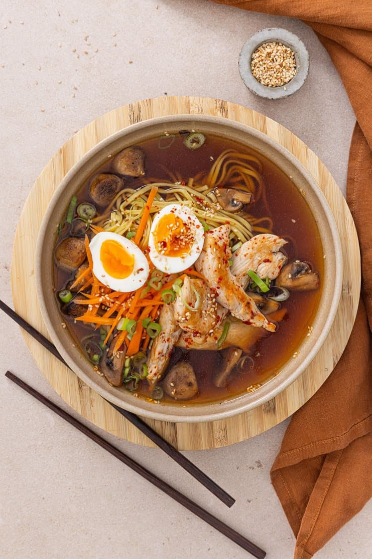 Ramen med spicy kylling, servert med bløtkokt egg, sopp, gulrot og sesamfrø