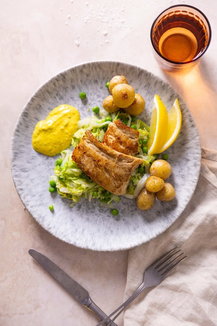 Stekt seifilet med kokte poteter, dampet kål og grønne erter, servert med karriremulade