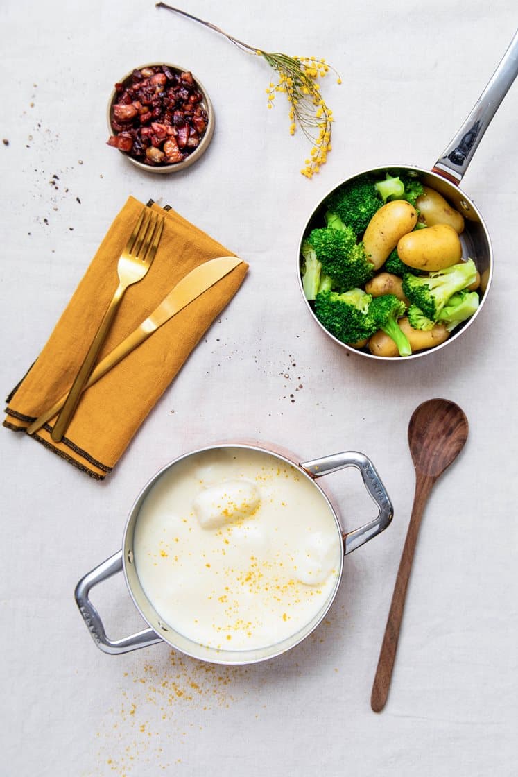 Fiskeboller i hvit saus med småpoteter og brokkoli, servert med sprøstekt bacon og karri