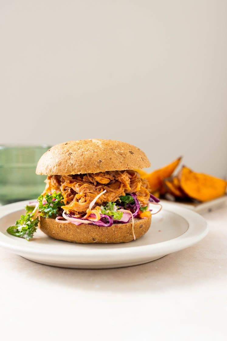 Pulled pork-burger med barbecuesaus, servert med maiscoleslaw og ovnsbakte søtpotetbåter