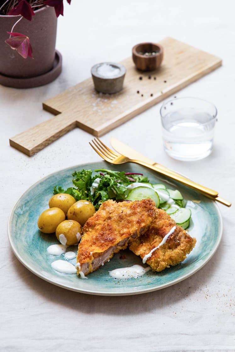 Svineschnitzel med kokte småpoteter, servert med syrlig agurksalat