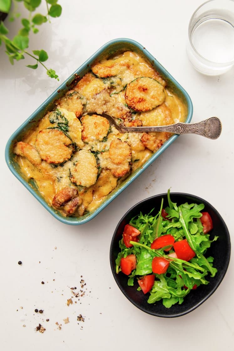 Gratinert steinsoppravioli i fløtesaus med squash og spinat, servert med ruccola- og tomatsalat
