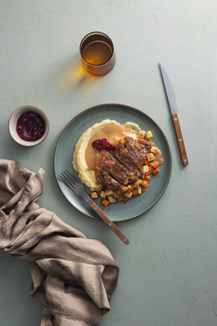 Krydderstekt svinenakke med ovnsbakte rotgrønnsaker, potetmos, soppsaus og rørte tyttebær