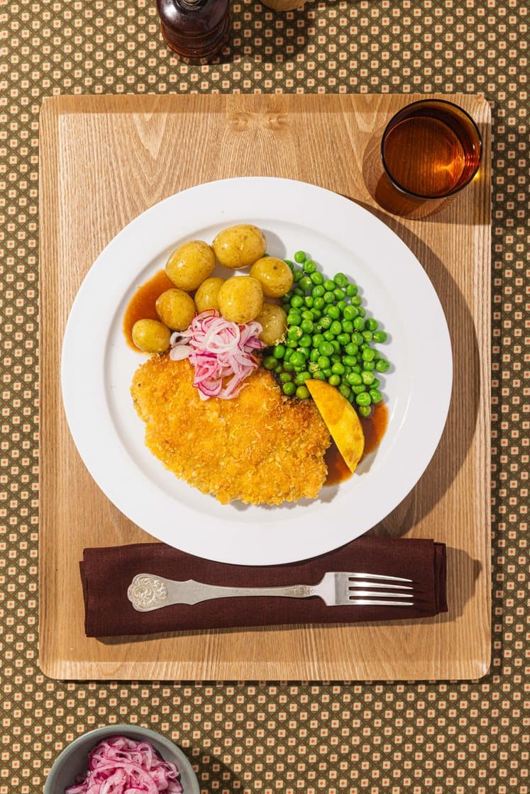 Svineschnitzel med lettsyltet rødløk, kokte småpoteter, erter og rødvinssaus