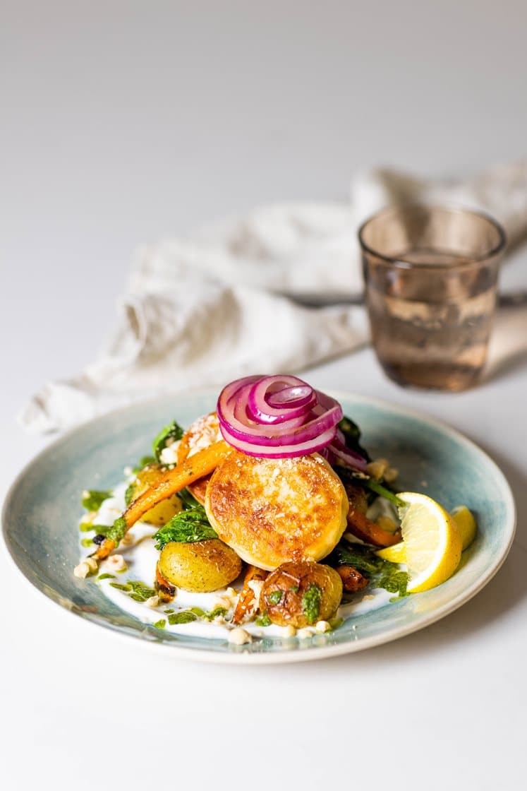 Fiskekaker med krydderbakte gulrøtter, småpoteter og spinat, servert med frisk yoghurt, pesto og hasselnøtter