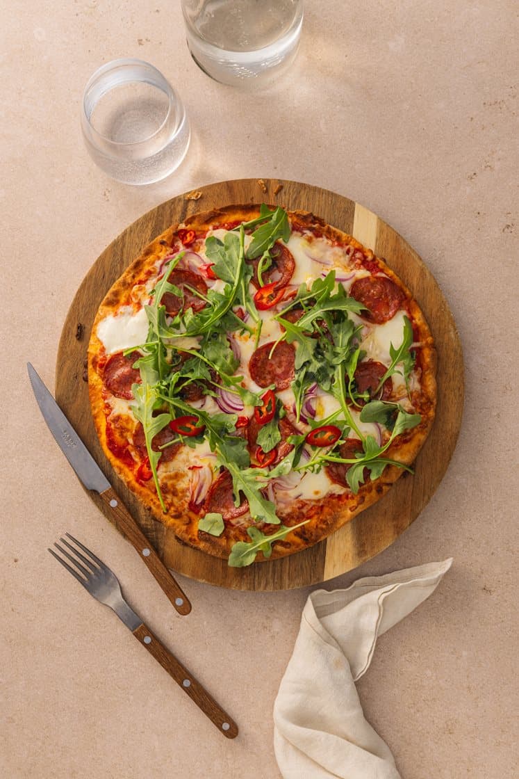 Pizza Diavola med mozzarella, pepperoni, rødløk og chili, servert med ruccola