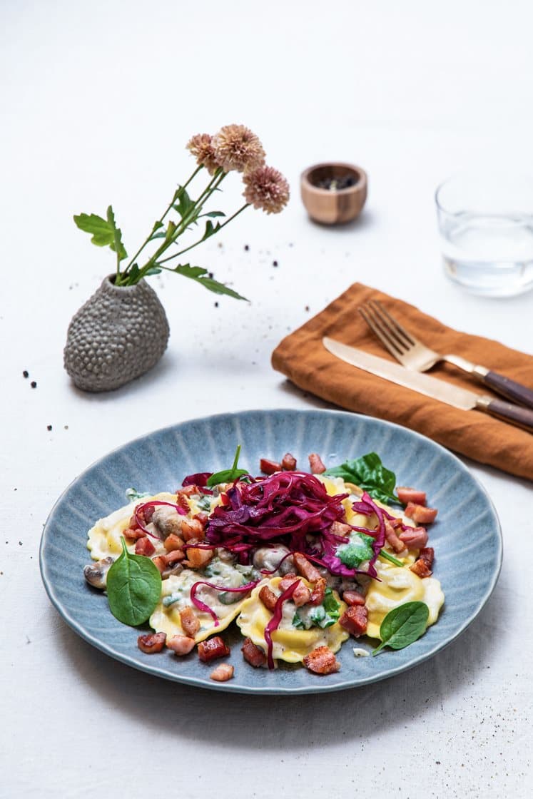 Steinsoppravioli med sjampinjong i kremet spinatsaus, toppet med sprøstekt bacon og syrlig rødkål