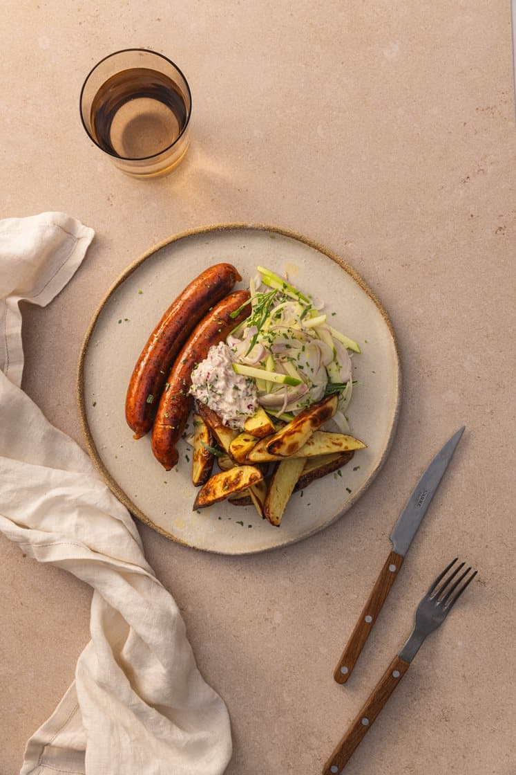 Trøffelpølse med eple- og fennikel slaw, karamelisert løkkrem og ovnsbakte båtpoteter