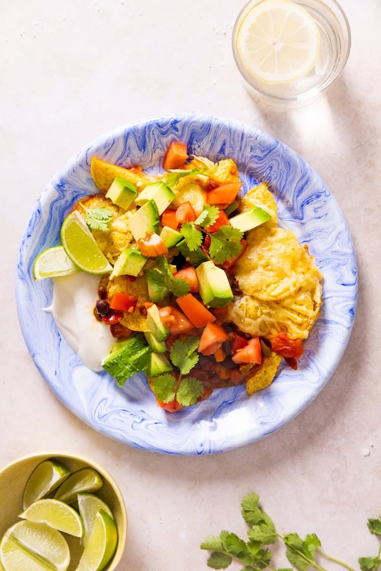 Gratinerte nachos med bønner, avokado og tomat, toppet med koriander og rømme