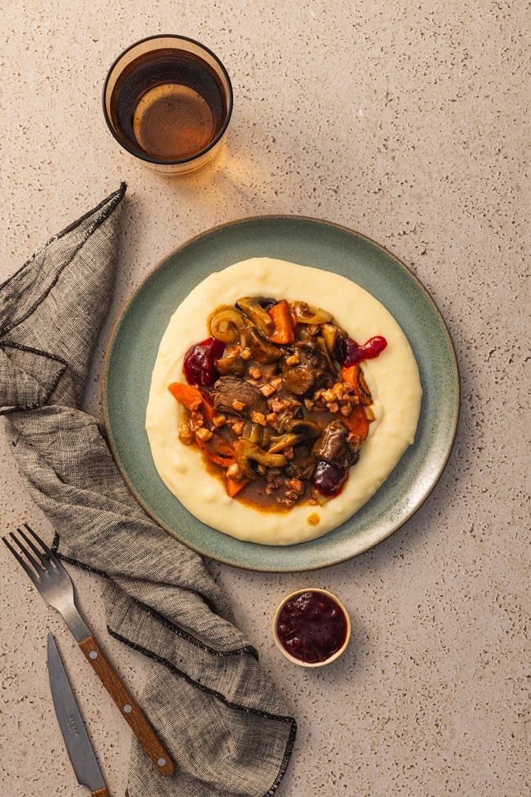 Mørkokt oksegryte med bacon, servert med potetmos, tyttebær og persille