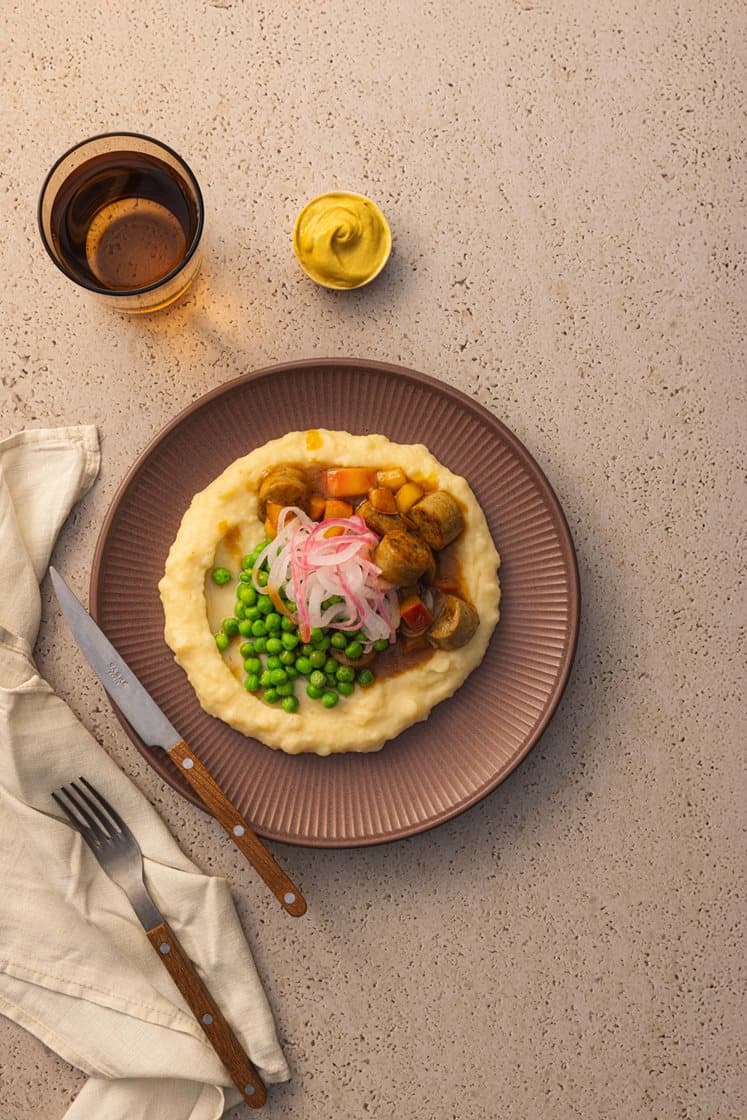 Karriwurst i eplesjy med karamellisert rødløk, potetmos, sennep og grønne erter