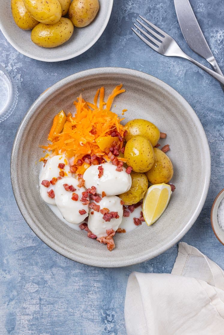 Fiskeboller i hvit saus med kokte poteter, råkostsalat med appelsin og sprøstekt bacon