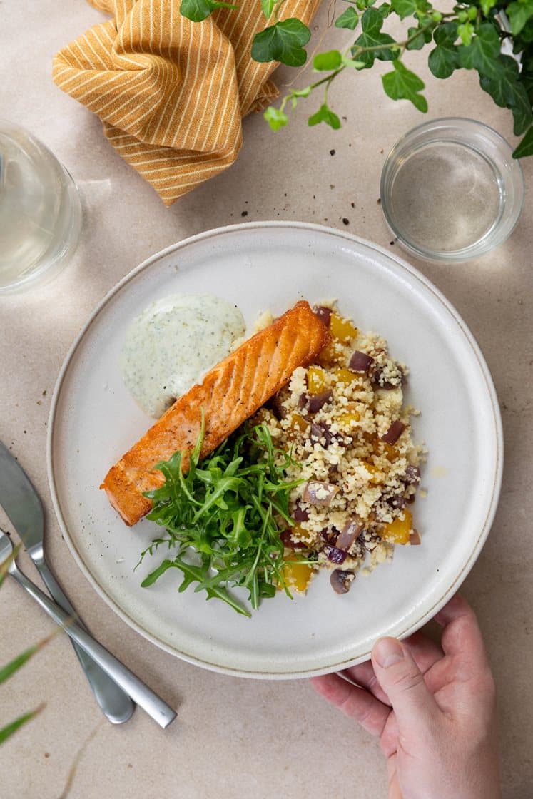 Pannestekt laksefilet og couscous med paprika og løk, servert med krydret yoghurtdressing og ruccola