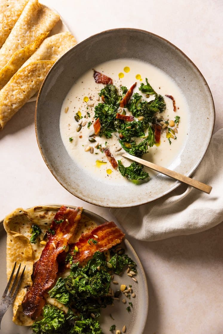 Hjemmelaget blomkålsuppe med grønnkålchips og ristede kjerner, servert med pannekaker og bacon