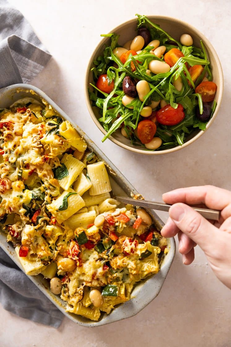 Gratinert pasta mezze maniche i fløtesaus med squash og spinat, servert med ruccola- og tomatsalat