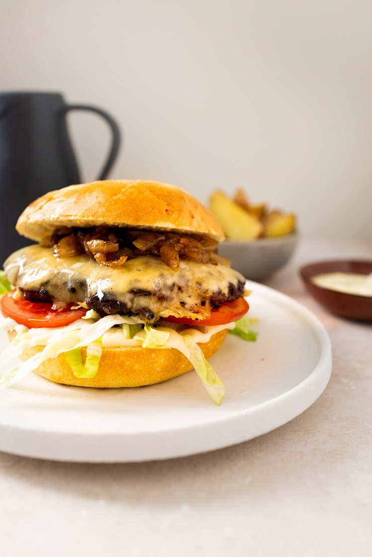 Smashburgere med stekt løk, tomat og strimlet salat, servert med aioli og ovnsbakte poteter