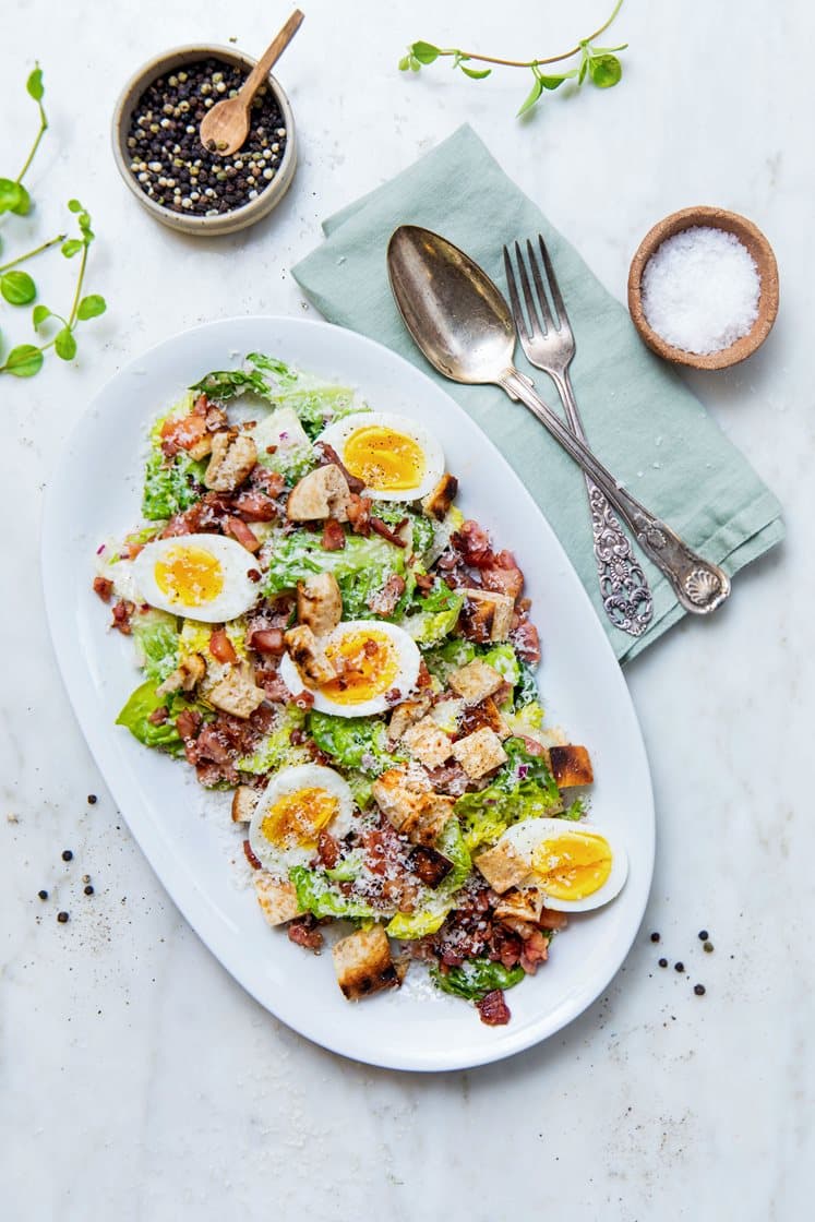 Cæsarsalat med kyllingfilet, sprøstekt bacon, kokte egg og brødkrutonger, toppet med Grana Padano