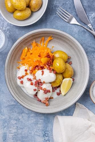Fiskeboller i hvit saus med kokte poteter, råkostsalat med appelsin og sprøstekt bacon