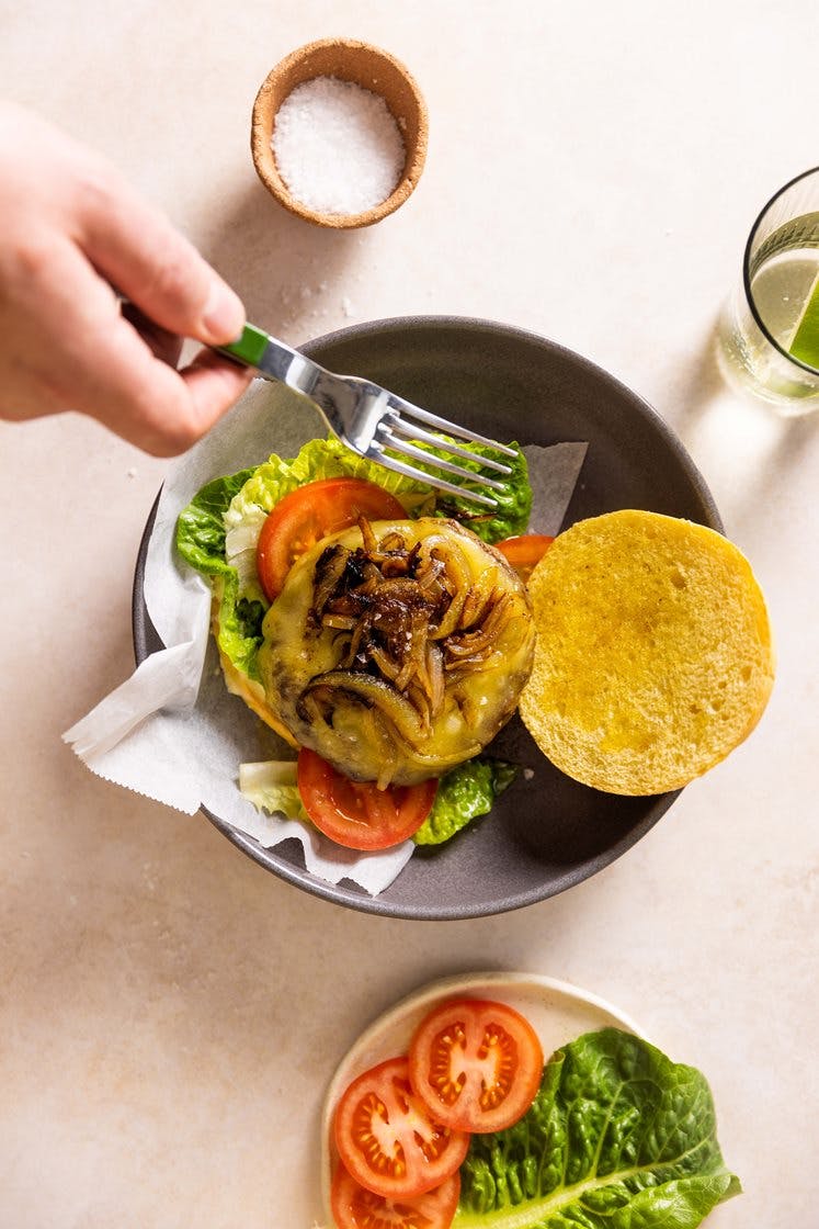 Cheeseburgere med stekt løk, tomat og hjertesalat, servert med aioli og ovnsbakte poteter