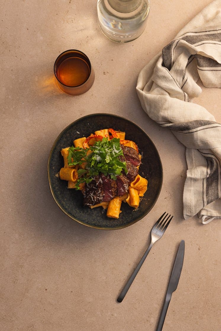 Paprikakremet pasta med tynnskåret mørbrad servert med ruccola og Grana Padano