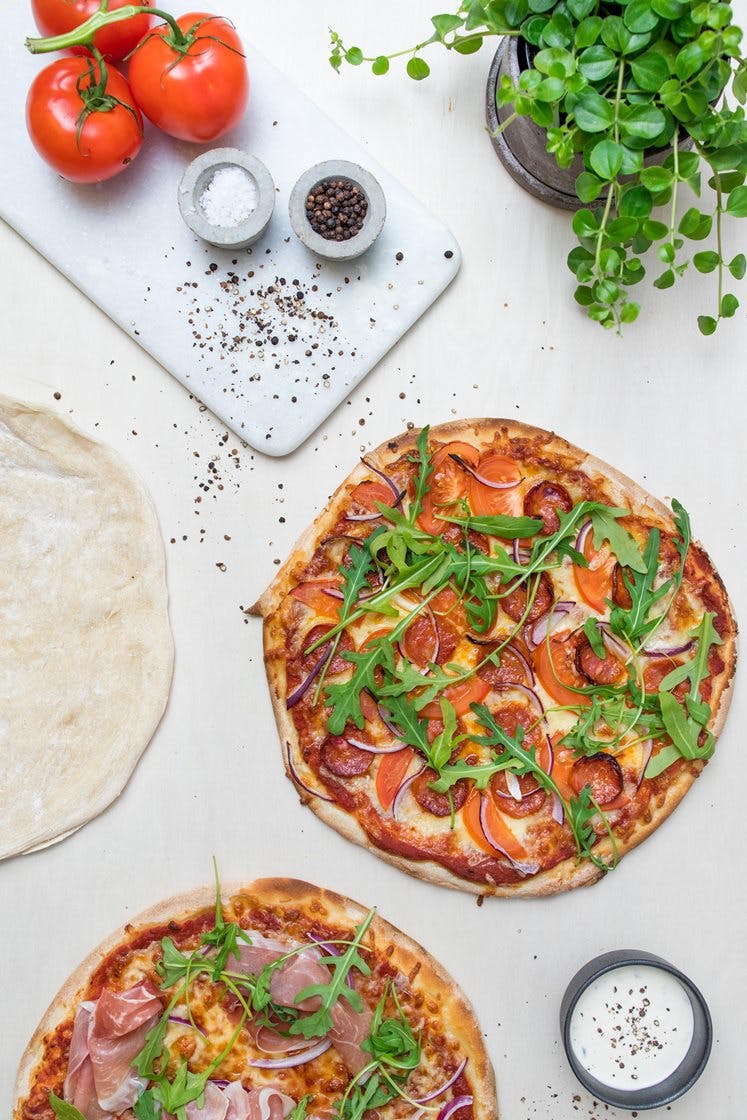 Rød og hvit pizza med mozzarella, parmaskinke og pepperoni på steinovnsbakte pizzabunner